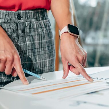 Businesswoman examining documents on a desk with a smartwatch and pen.