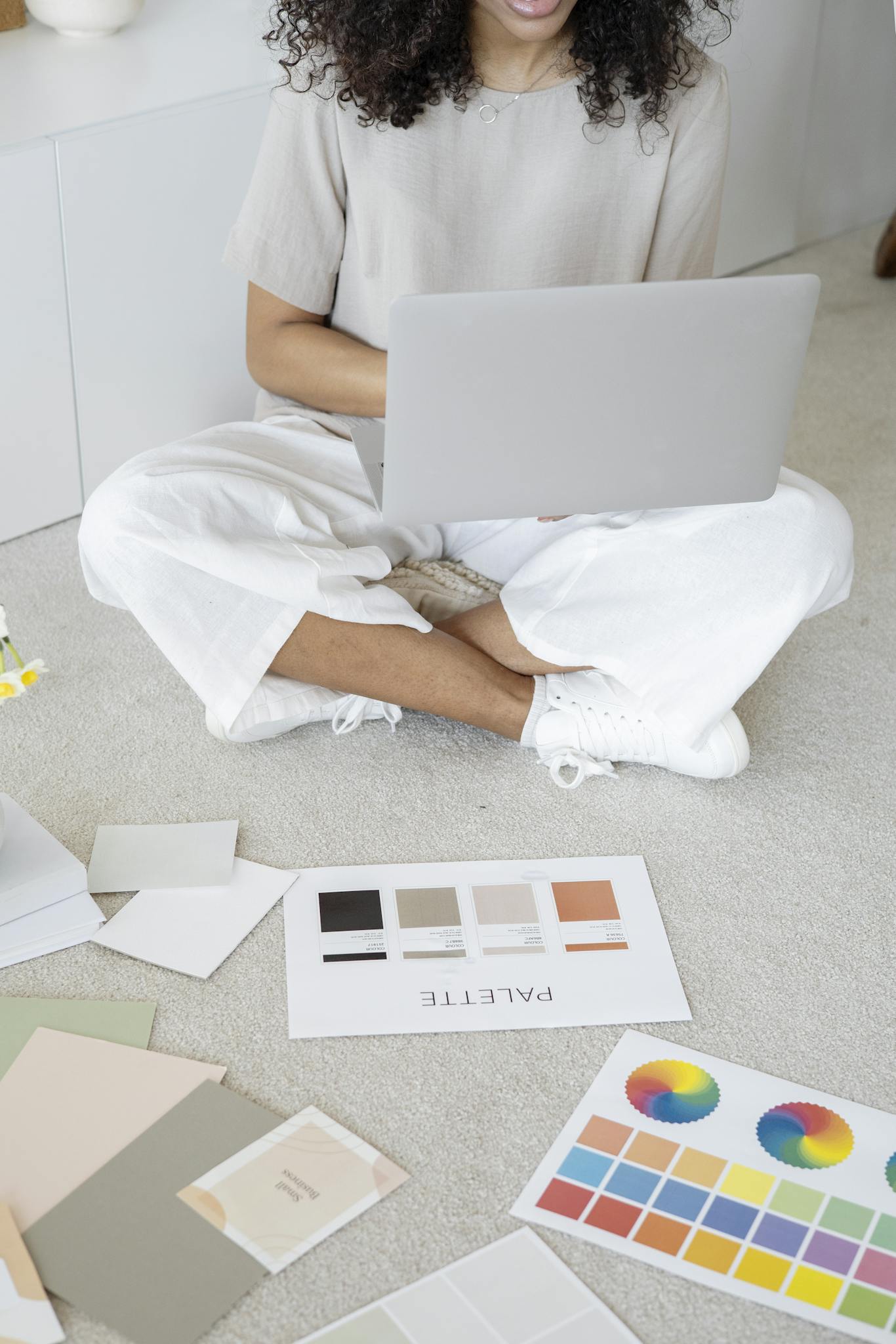 Young woman reviews color palettes for design project on laptop, sitting indoors.